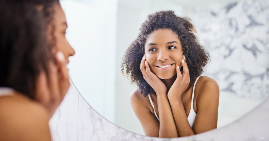 Woman looking in mirror considering injectables